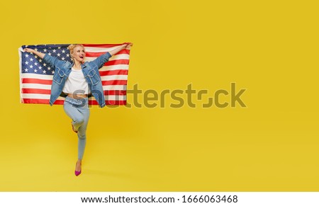 American girl. Happy young woman in denim clothes holding USA flag isolated on yellow background