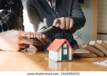 Close up of Businesswoman and customer pointing and using smartphone for buying house. Bank manager concept.
