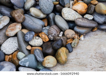 Multi-colored stones. Gray and yellow. White and black. Big and small. In the open air.
