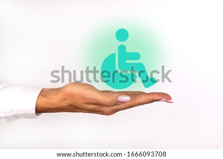 Conceptual image, care for handicapped person. Female hand with wheelchair icon on white background.