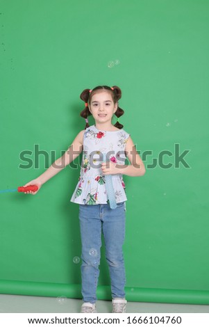 portrait of a young funny girl of eight years old with a funny hairstyle in a good mood and grimaces