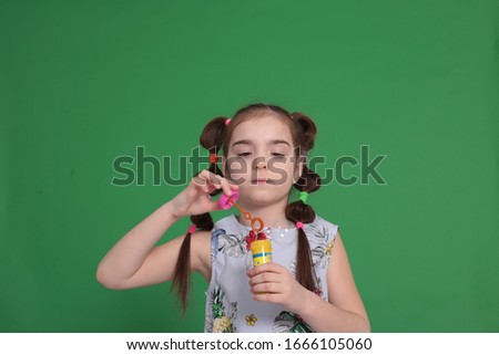 portrait of a young funny girl of eight years old with a funny hairstyle in a good mood and grimaces