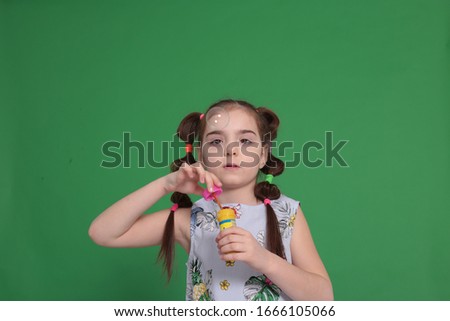 portrait of a young funny girl of eight years old with a funny hairstyle in a good mood and grimaces
