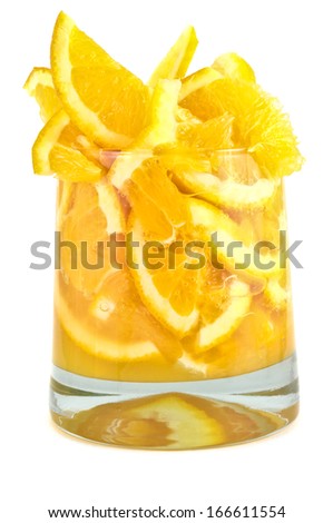 Glass with pieces of the orange on white background. 