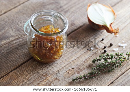 Homemade onion marmalade (jam) in a glass jar on  rustic wooden table.Selective focus.