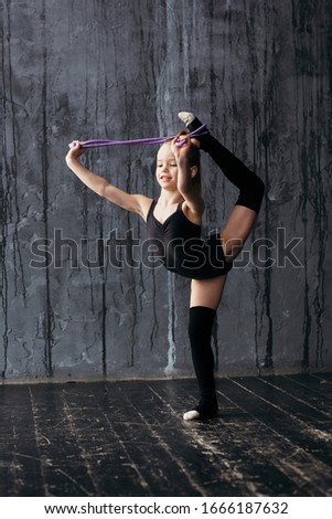 Gymnast performs the exercise standing on one leg and using equipment.