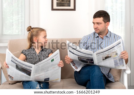 Shot of a daughter and dad spending time together at home. They sit on the sofa and read the newspapers together same way.  Daughter imitates her father. Royalty-Free Stock Photo #1666201249