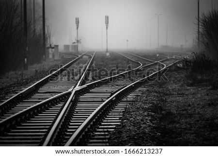Railroad junction with track switches disappearing in mist - monochrome image Royalty-Free Stock Photo #1666213237