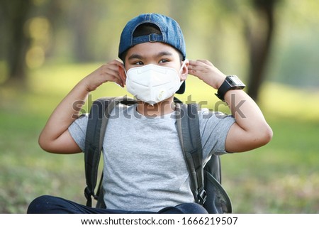 A young Asian boy , 7 Years Old , wear mask to protect against dust PM 2.5 and germs Royalty-Free Stock Photo #1666219507