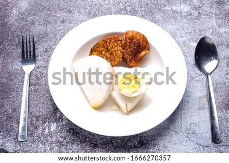 A picture of "nasi impit, "tempe", "pegedil" and boiled egg in the plate prepared for "lontong".