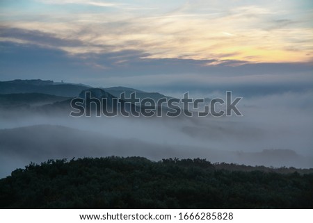 Misty morning among trails and mountains. Dawn in the rocks. Traveling in beautiful places. Sky in the clouds