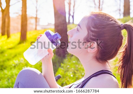 Woman runner's drinking a water after run. Fitness, people and healthy lifestyle. Sports morning in the park. Tinted photo