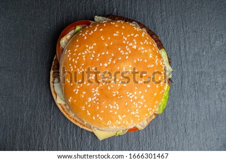 Burger on a slate, black stone tableware. Top view. Close up.