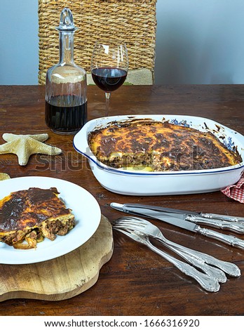 Greek Moussaka . Isolated Image. Homemade traditional Iconic Greek eggplant dish  served on a plate accompanied with a glass of red wine. Stock Image.