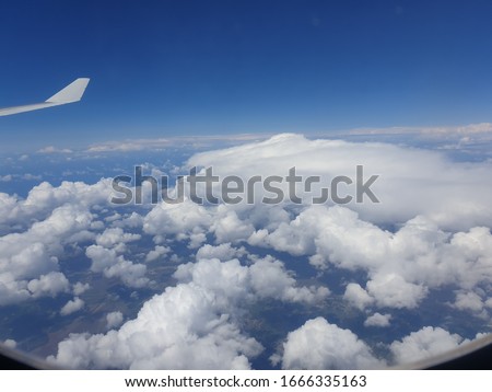 View through an air plane window with blue sky and clouds - stock  photo