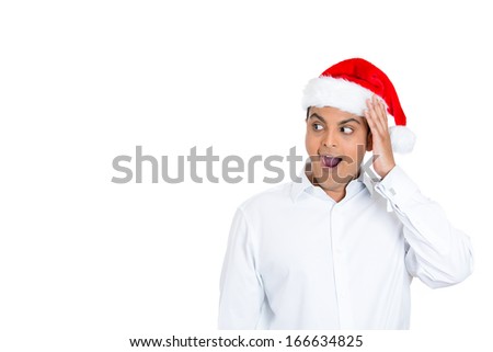 Closeup portrait of shocked surprised man wearing red santa claus hat, hand on cheek, mouth eyes wide open looking to left side, isolated on white background. Positive human emotion facial expression