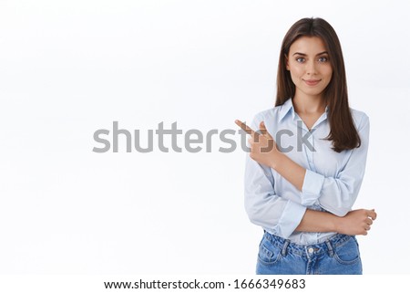 Confident professional young woman in blue blouse pointing finger upper left corner and looking at camera persuade customer make right choice and sign deal with her company, white background