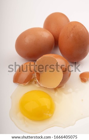 Broken chicken egg and eggs scattered on a white background. Close up.