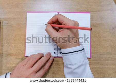 A picture of a business person holding a pen and taking notes in a notebook