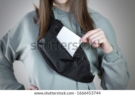 Girl holds a clean white square piece of paper. Close up. Isolated on a gray background.