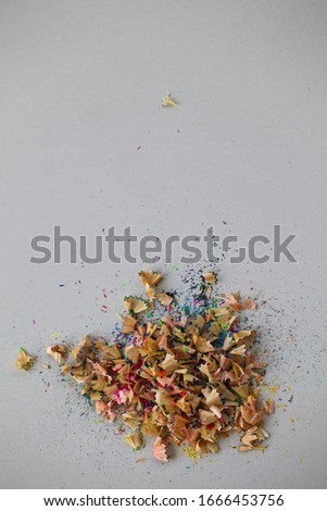 Close up pencil sharpener with crayon shavings on white table.