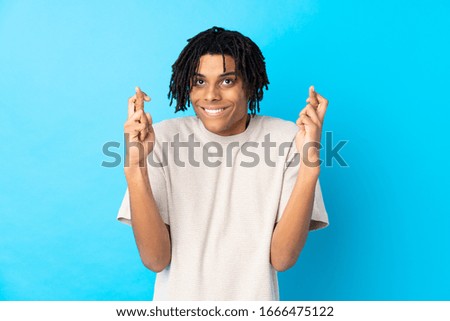 Young African American man over isolated blue background with fingers crossing and wishing the best