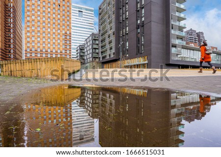 A city with modern skyscrapers and corporate buildings during daytime reflecting in a puddle of water