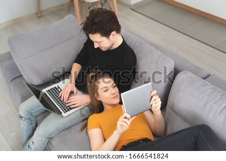 Couple using fast home internet with laptop and digital tablet. Woman and man on sofa in living room Royalty-Free Stock Photo #1666541824