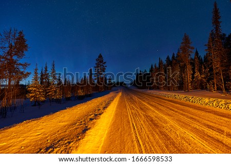 Jokkmokk, Sweden - 03 02 2019: road to Jokkmokk before Polecirkeln-Arctic Circle. northernlights showed short time while roadtrip to the north at mainroad. Stopped to make photos with warninglamps on.