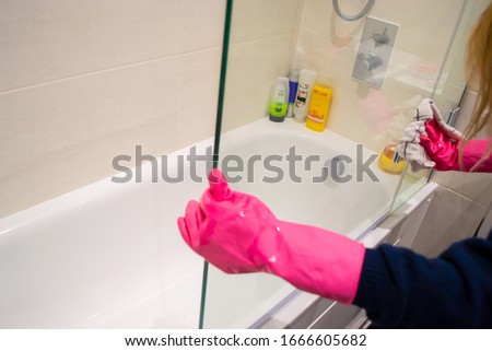 Cleaning a shower screen wearing pink rubber gloves Royalty-Free Stock Photo #1666605682