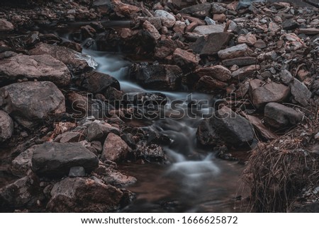 A small stream creates a magnificent effect as the water flows over the rocks on a cold winter day