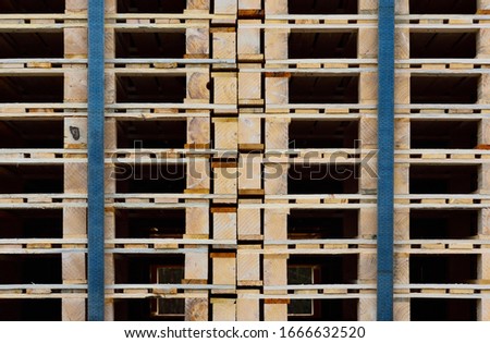 Close-up, texture and background of many wooden pallets stacked on top of one another and held together by tension belts