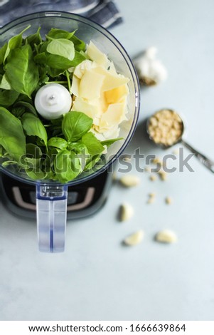 Overhead view of ingredients for fresh pesto in a food processor on a light grey kitchen countertop background Royalty-Free Stock Photo #1666639864