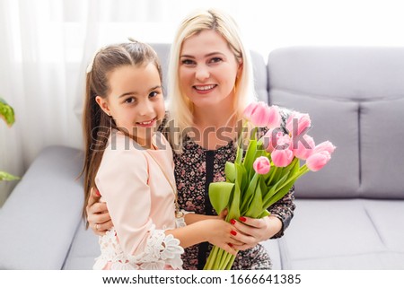 Happy mother's day. Child daughter congratulates moms and gives her flowers tulips