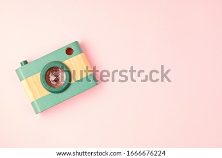 Flat lay with toy wooden camera and hearts over pink background. Social media, posts, likes, followers, online photography classes concept. Top view, copy space.