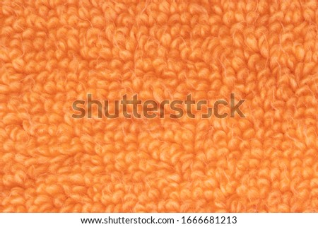 Orange fabric texture. Close-up of a orange fluffy terry bath towel or textile backround. Macro photograph. Beautiful bright backdrop.