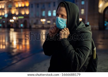 Teenager with backpack putting on mask in the city at night, cornavirus Royalty-Free Stock Photo #1666688179