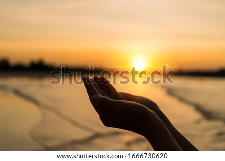 Woman hands place together like praying in front of nature blur beach sunset sky background.