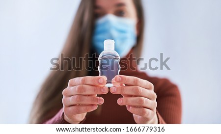 Woman in protective mask and with antibacterial antiseptic gel for hands disinfection and health protection prevention during flu virus outbreak, epidemic and infectious diseases Royalty-Free Stock Photo #1666779316