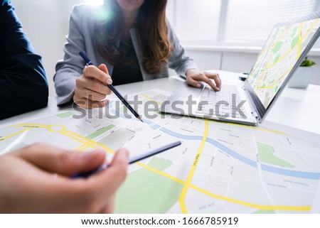 Two People Looking At City Map With Laptop At Table