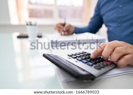 Cropped Image Of Businessman Calculating Invoice At Desk Royalty-Free Stock Photo #1666789033