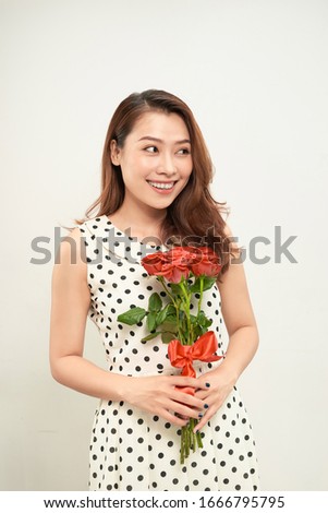 Portrait of a pretty young woman dressed holding bouquet of roses isolated over white background