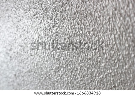 Blurred is Slight roughness of the cement wall surface.
