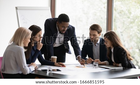 Confident african American male boss work cooperate with diverse team at office briefing, focused biracial businessman head meeting, collaborate discuss business ideas with colleagues at meeting Royalty-Free Stock Photo #1666851595