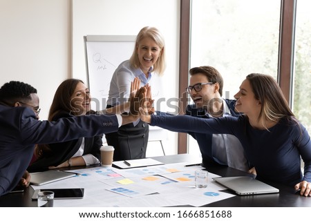 Excited motivated diverse businesspeople give high five show unity and support at company meeting, overjoyed multiracial coworkers engaged in teambuilding activity in office, collaboration concept Royalty-Free Stock Photo #1666851688