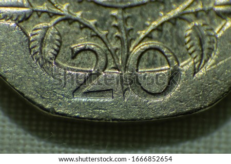 Macro photo of a twenty pence coin. Extreme close up of a 20p coin. Focus is on the ‘20’ of the coin. Coin is resting on a sheet of white fabric.