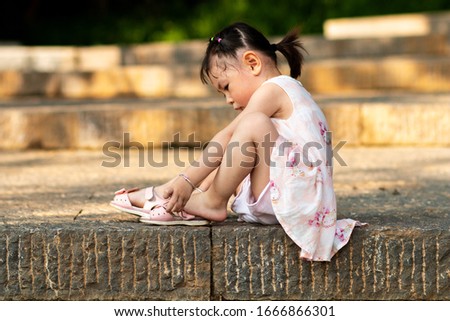 The little girl sitting on the steps wearing sandals Royalty-Free Stock Photo #1666866301