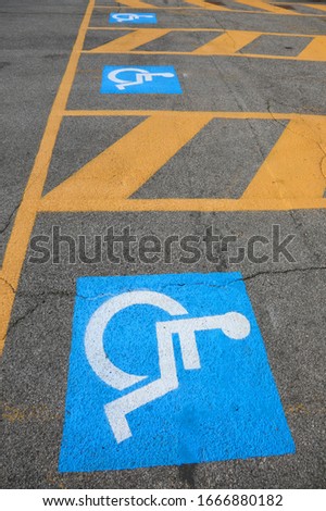 blue and white signs on the asphalt indicating a parking for disabled people