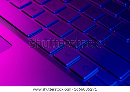 Close up view of a modern laptop computer keyboard keys. Soft lightning. Computer keyboard close up in pink and blue tones