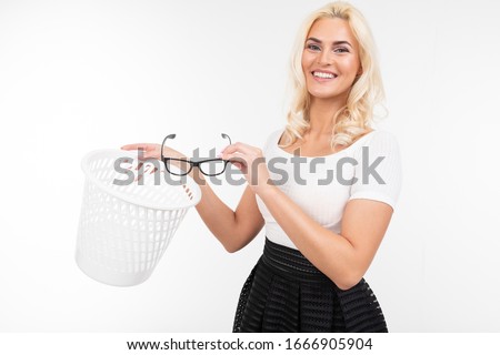 charming elegant girl ejectively throws glasses for sight in an urn on a white studio background with copy space Royalty-Free Stock Photo #1666905904